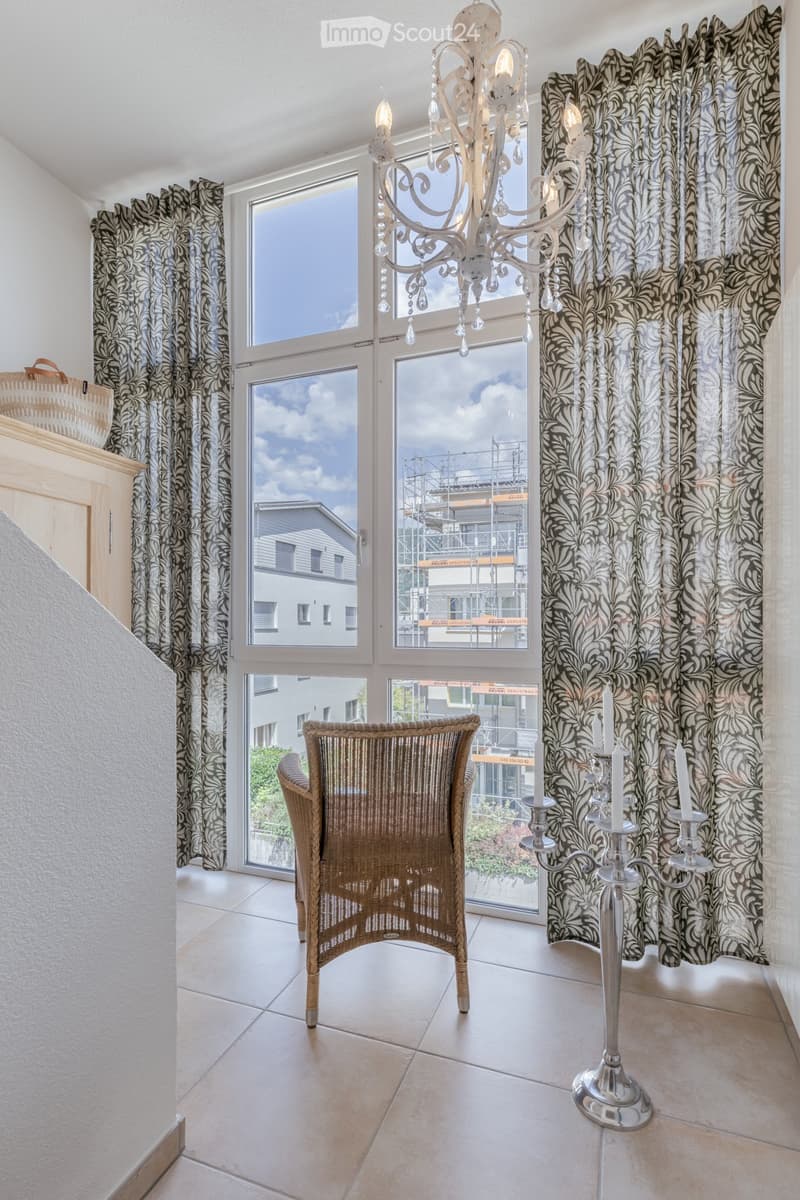 Bright room with large windows, a wicker chair, and a silver candelabra on the floor.