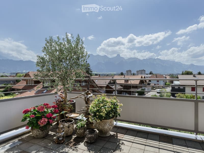 Balcony with potted plants, decorative lanterns, and a scenic mountain view in the background.
