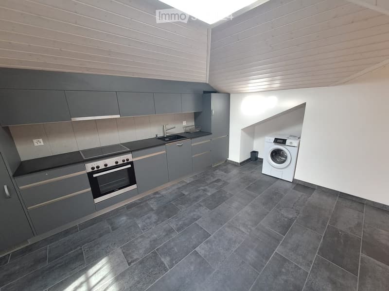 Modern kitchen with grey cabinets, dark countertops, and a built-in oven. Includes a sink, faucet, and a private washing machine in the corner.