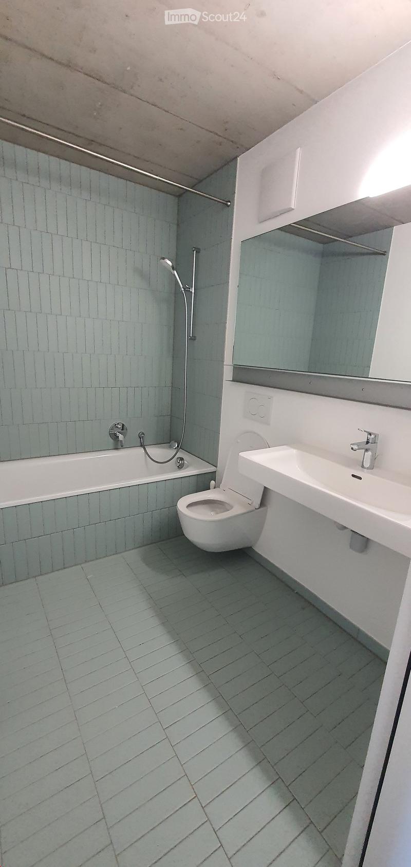 Modern bathroom with light blue tiles, white fixtures, and a sleek design.