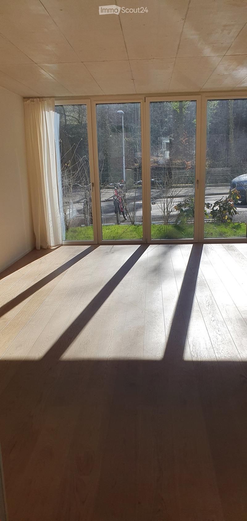 Empty room with wooden flooring and large glass doors leading to an outdoor area. No furniture or equipment visible.