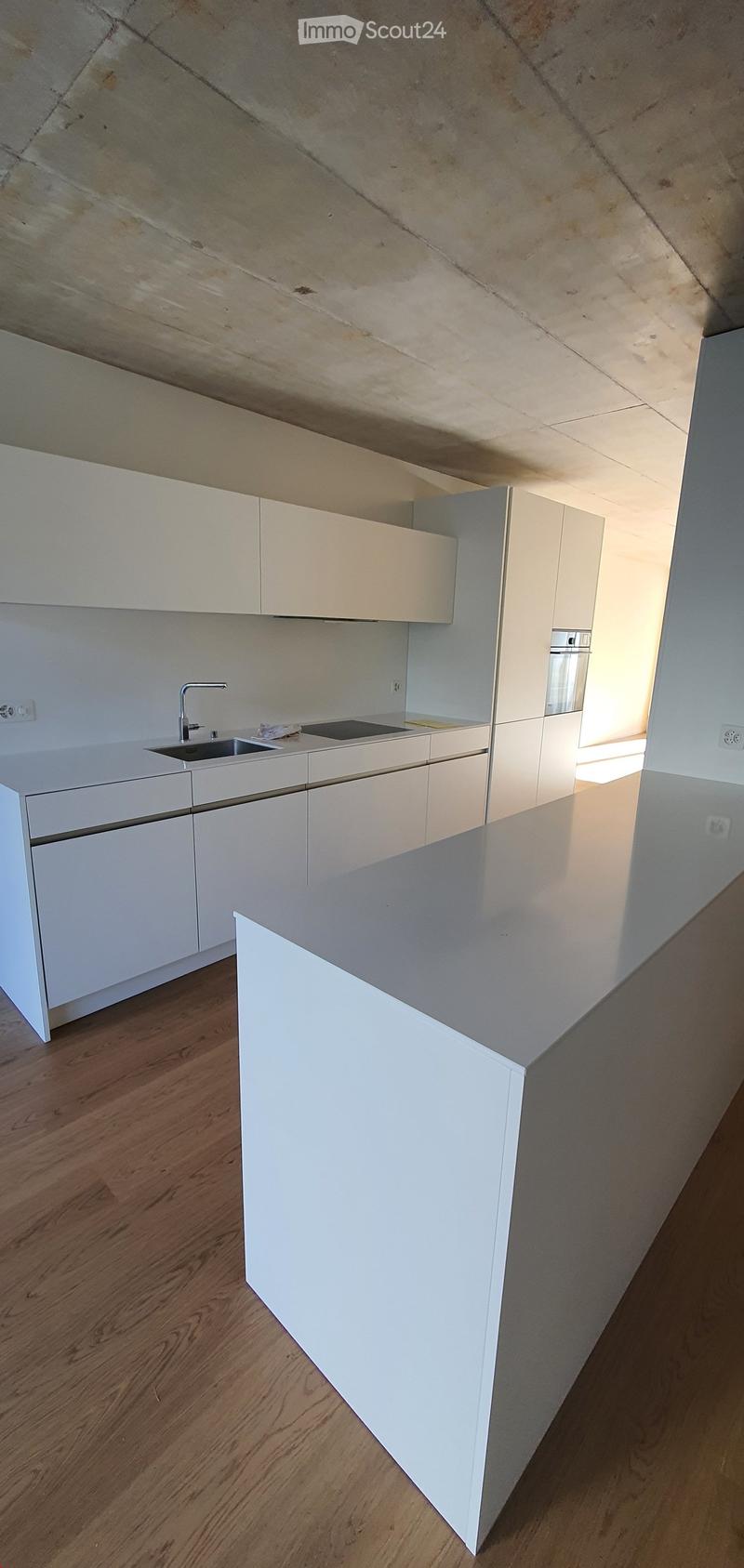 Modern kitchen with white cabinets, a central island, and a sink with a faucet. The floor is made of light wood.