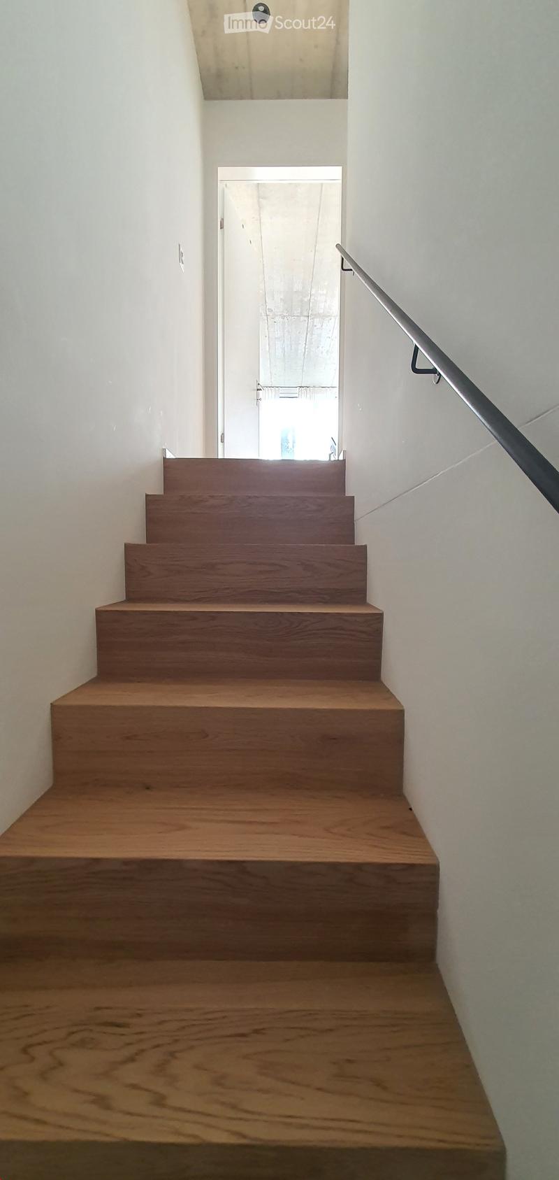 Wooden staircase with a modern metal railing, leading to a doorway at the end.