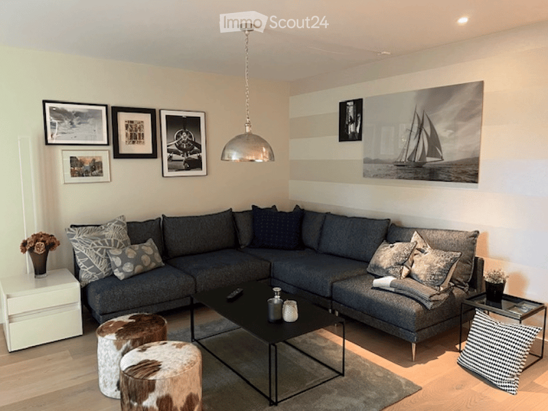 Modern living room with a grey sectional sofa, black coffee table, decorative pillows, and a pendant light fixture.