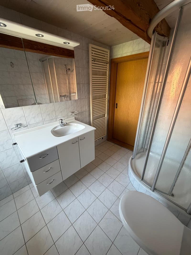 Modern bathroom with a white sink, mirrored cabinet, tiled floor, bathtub, and a glass-enclosed shower area.