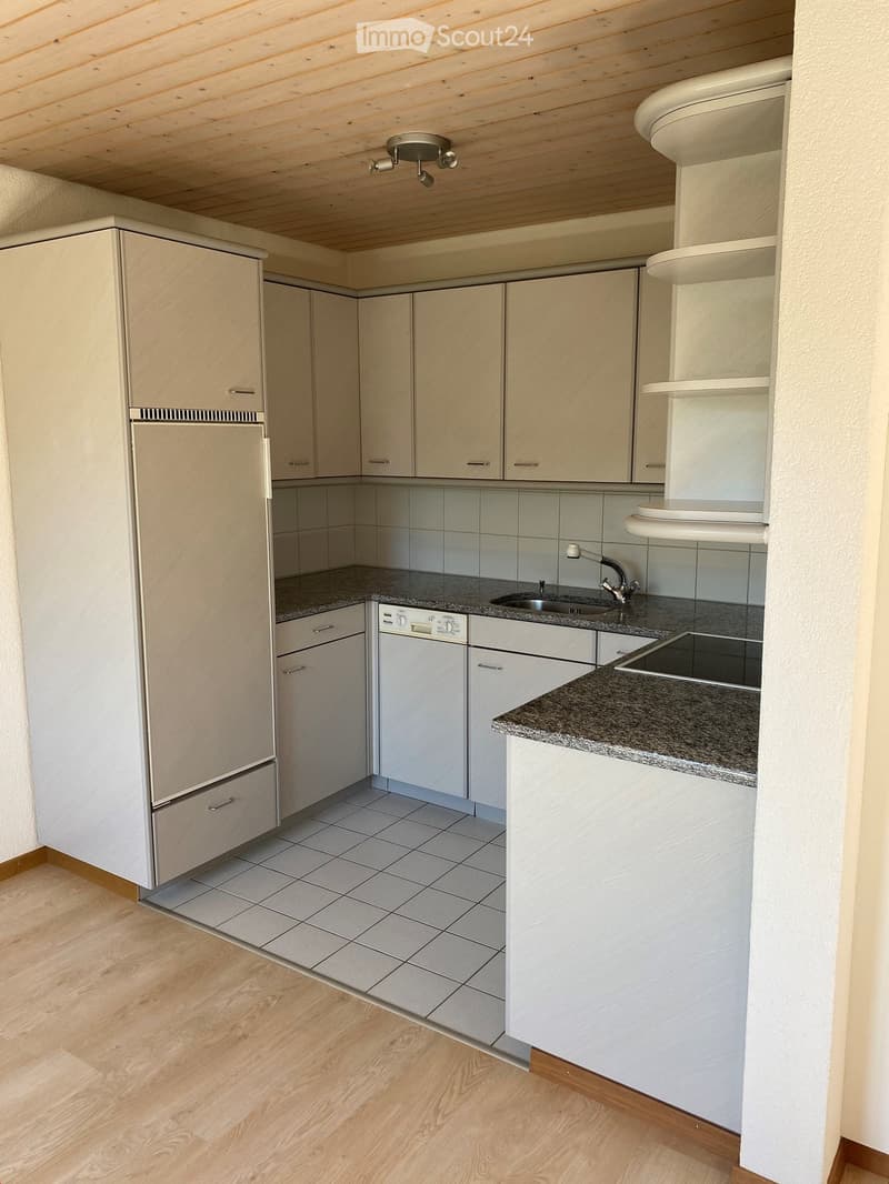 Modern kitchen with light wood cabinets, granite countertops, stainless steel appliances, and a tiled backsplash.