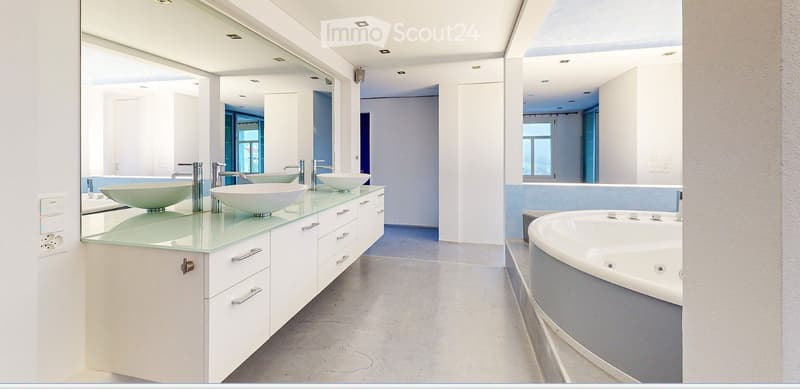 Modern bathroom with a large mirrored wall, three sinks on a glass countertop, and a bathtub with a sleek design.