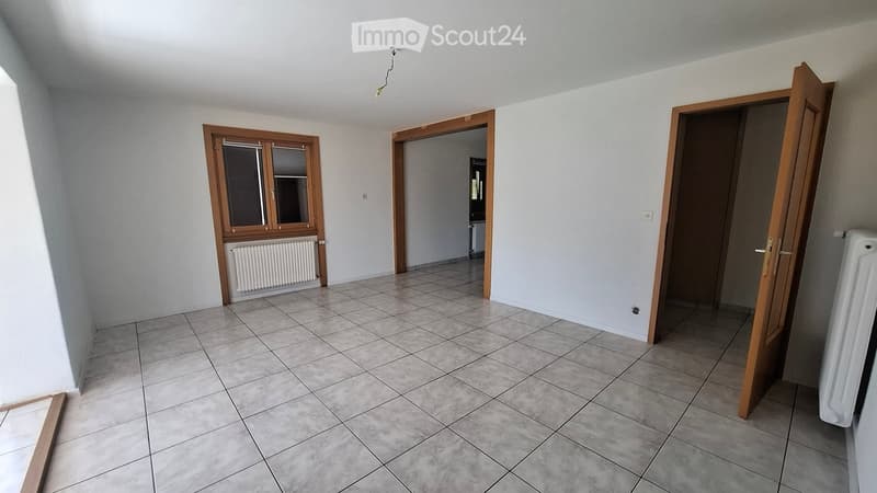 Empty room with tiled floor, white walls, wooden doors, and a window with blinds. No furniture or equipment present.