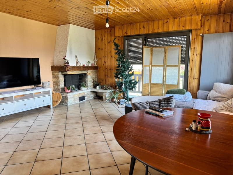Cozy living room with wooden walls and ceiling, tiled floor, fireplace, sofa, coffee table, TV, and decorative items.