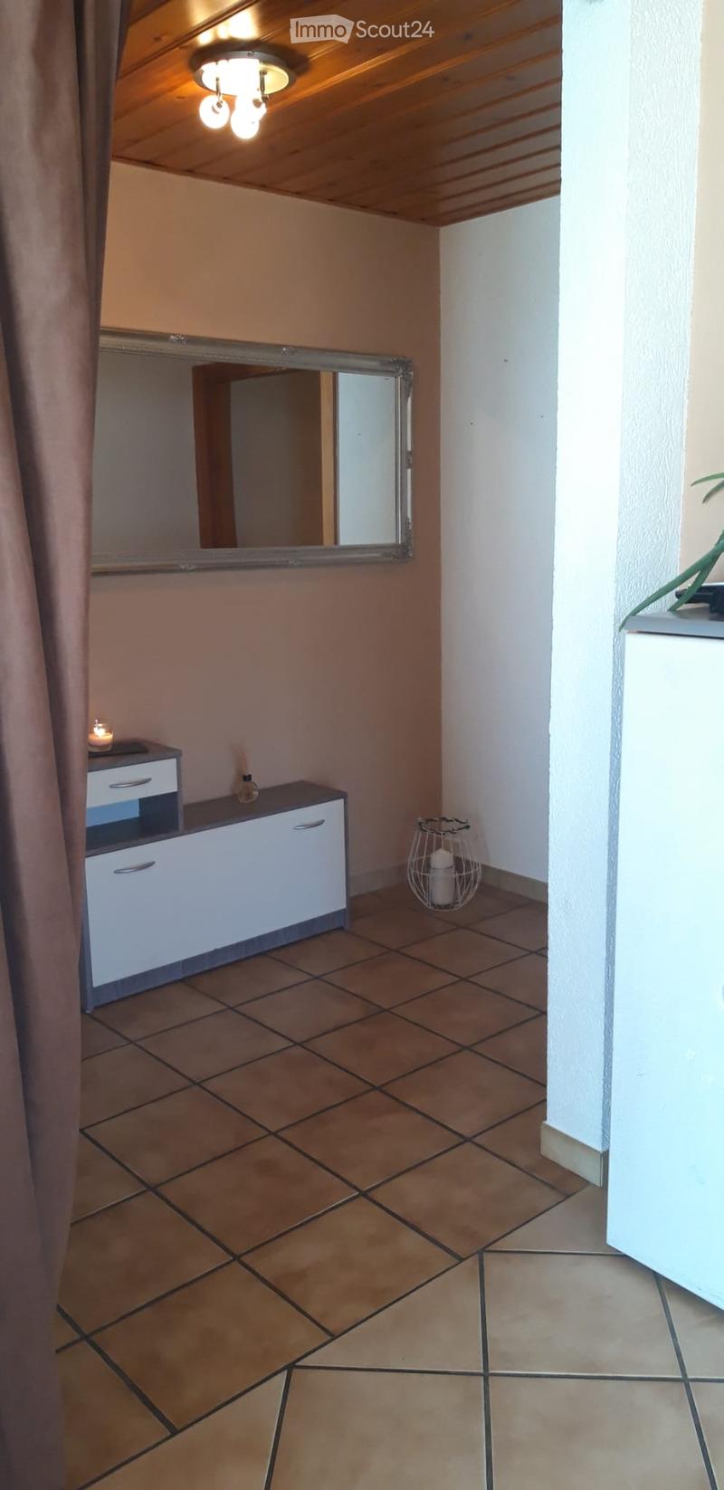 Hallway with tiled floor, white walls, a small cabinet, a mirror, and a decorative candle holder.