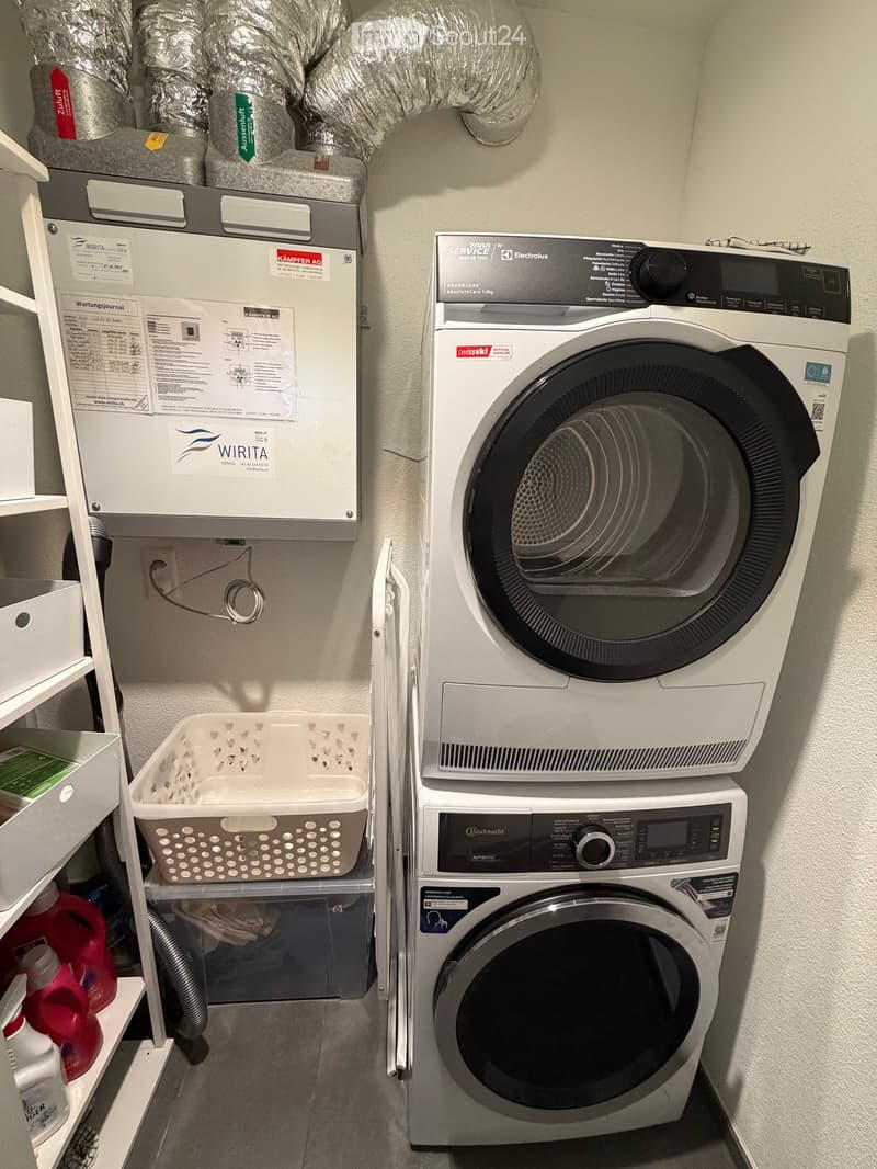 Laundry area with a washing machine, dishwasher, shelf, and laundry basket.