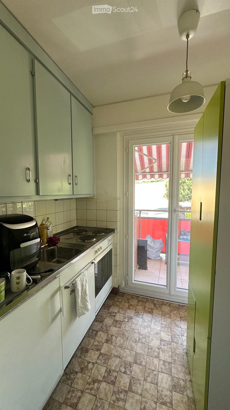 Modern kitchen with white cabinets, tiled floor, and a sliding glass door leading to a balcony.