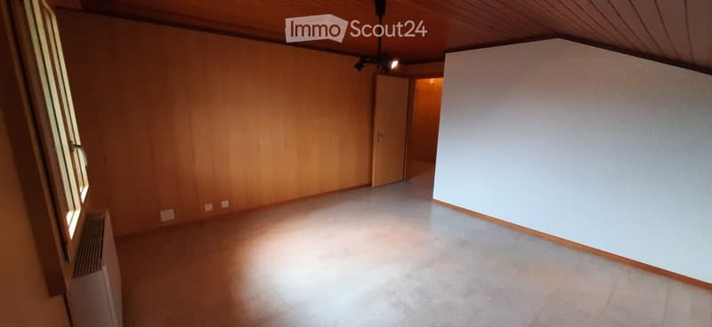 Empty room with wooden walls, tiled floor, and a door leading to another space.
