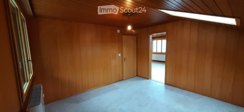 Empty room with wooden walls and ceiling, tiled floor, and a single door leading to another space.