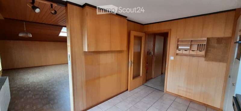 Empty room with wooden walls, tiled floor, and built-in wooden cabinetry. No furniture or equipment present.