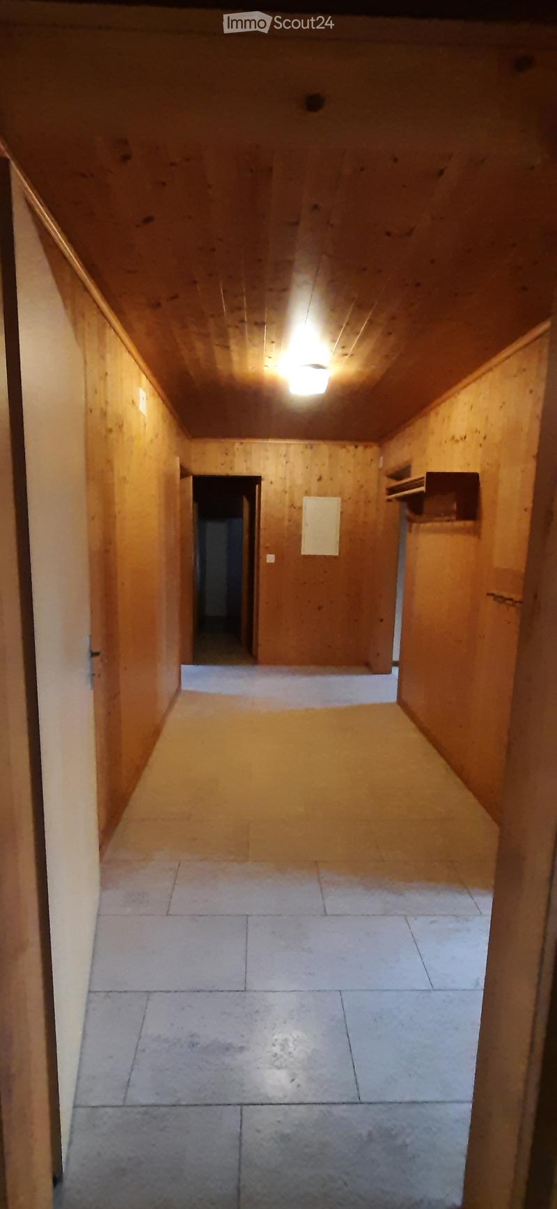Wooden-paneled hallway with tiled floor, small built-in shelf, and a recessed ceiling light.