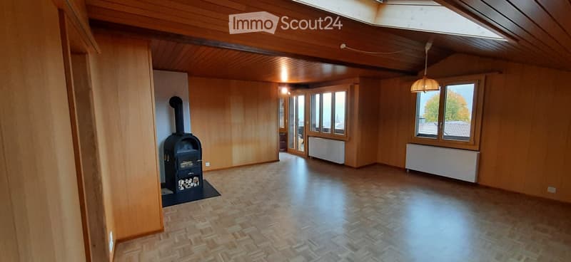 Empty room with wooden walls, wooden ceiling, and a fireplace. Large windows and a skylight provide natural light.