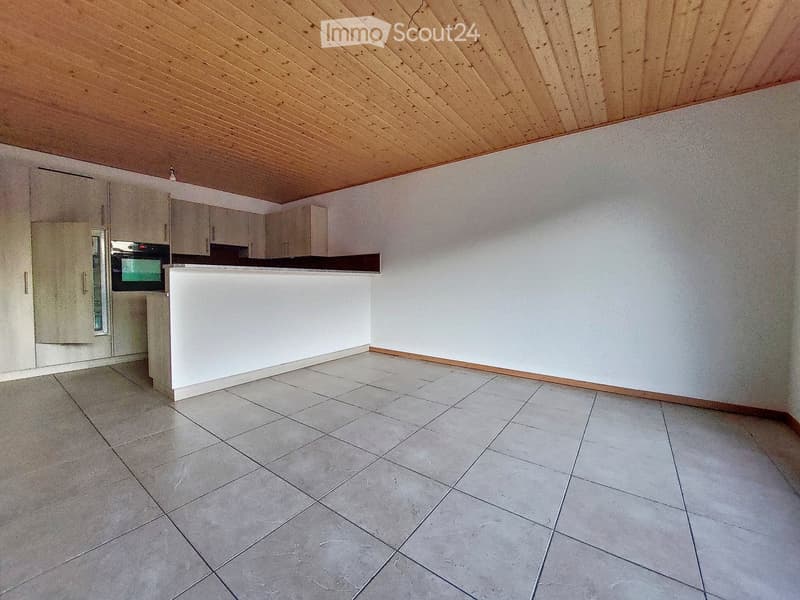 Empty kitchen with tiled floor, white walls, and built-in cabinets. No furniture or appliances are present.