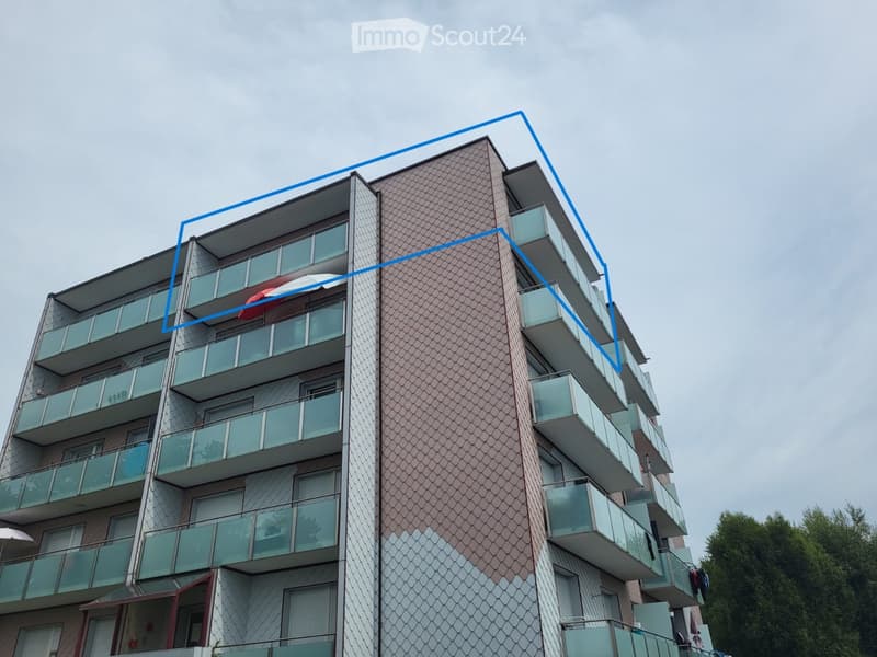 Modern multi-story apartment building with glass balconies and a distinctive geometric facade.