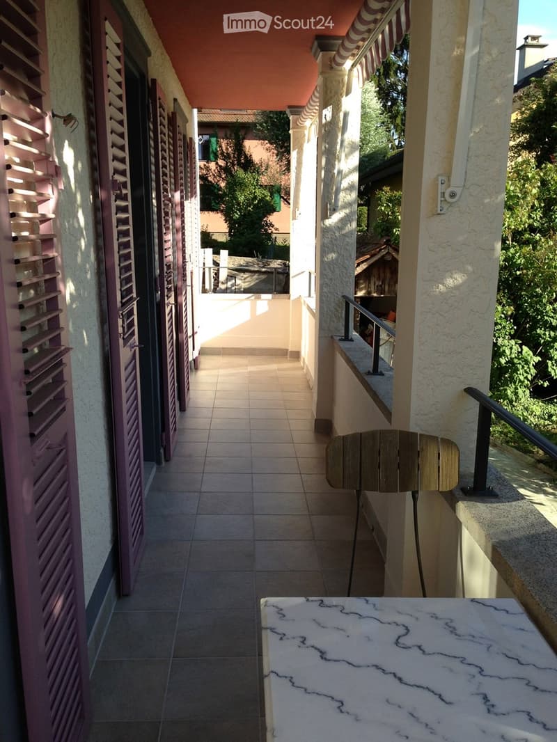 Balcony with tile floor, wooden chair, marble table