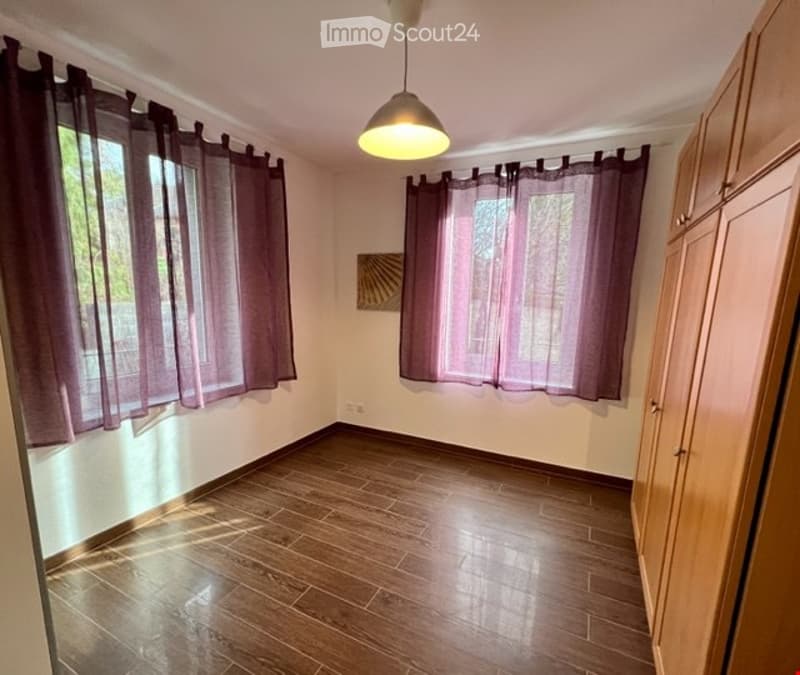 empty room, wooden floor, white walls, two windows with purple curtains, wooden cabinets