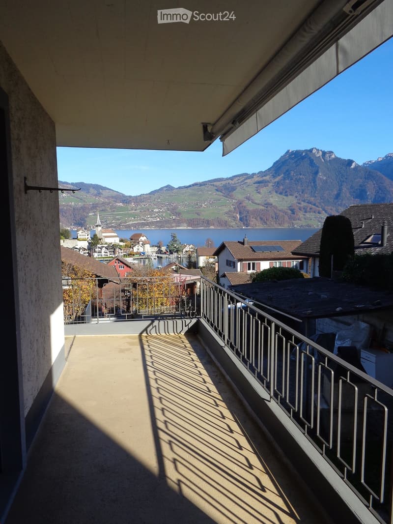 Balcony with metal railing, overlooking a scenic lake and mountain landscape.