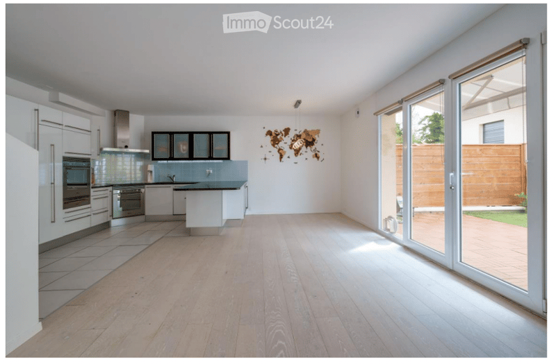 Modern kitchen with white cabinets, stainless steel appliances, a central island, and large sliding glass doors leading to a patio.
