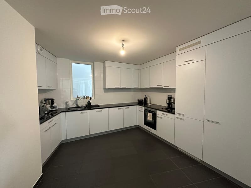 Modern kitchen with white cabinets, black countertops, and black tiled floor. Features a sink, oven, coffee maker, and microwave.