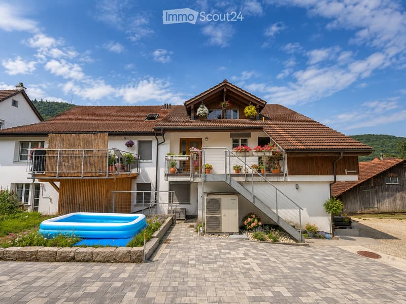 Two-story house with a tiled roof, balconies, and a swimming pool in the front yard.