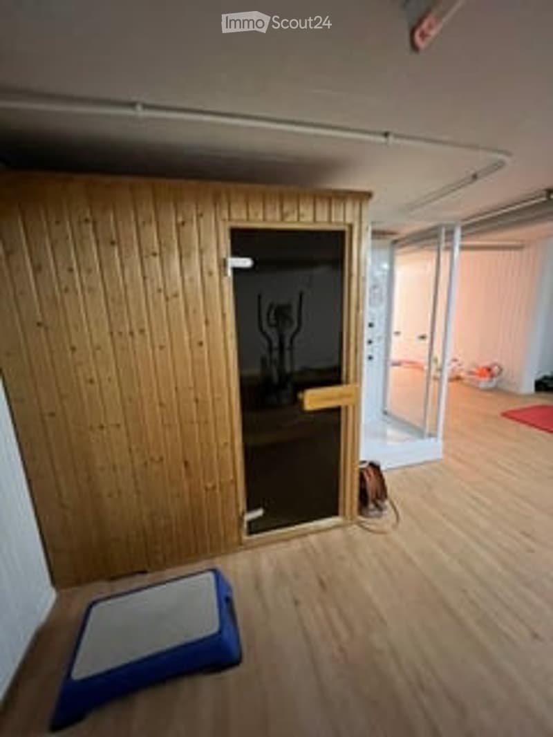 Empty room with wooden flooring, white walls, and a glass door leading to another space. No furniture or equipment visible.