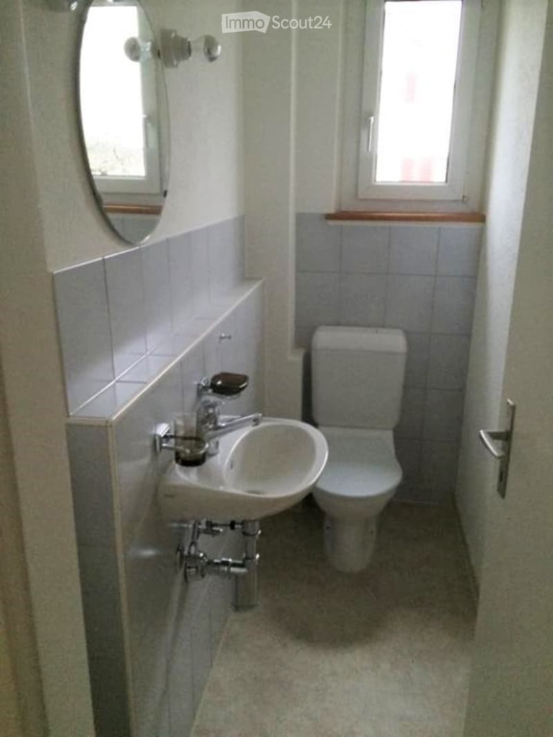small bathroom with sink, toilet, mirror, and window