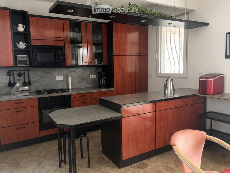 Modern kitchen with wooden cabinets, granite countertops, stainless steel appliances, and a small dining area with a table and chairs.