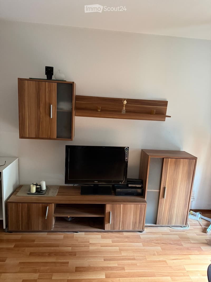 wooden entertainment center, flat screen TV, candles, wall shelves, small table, power outlets