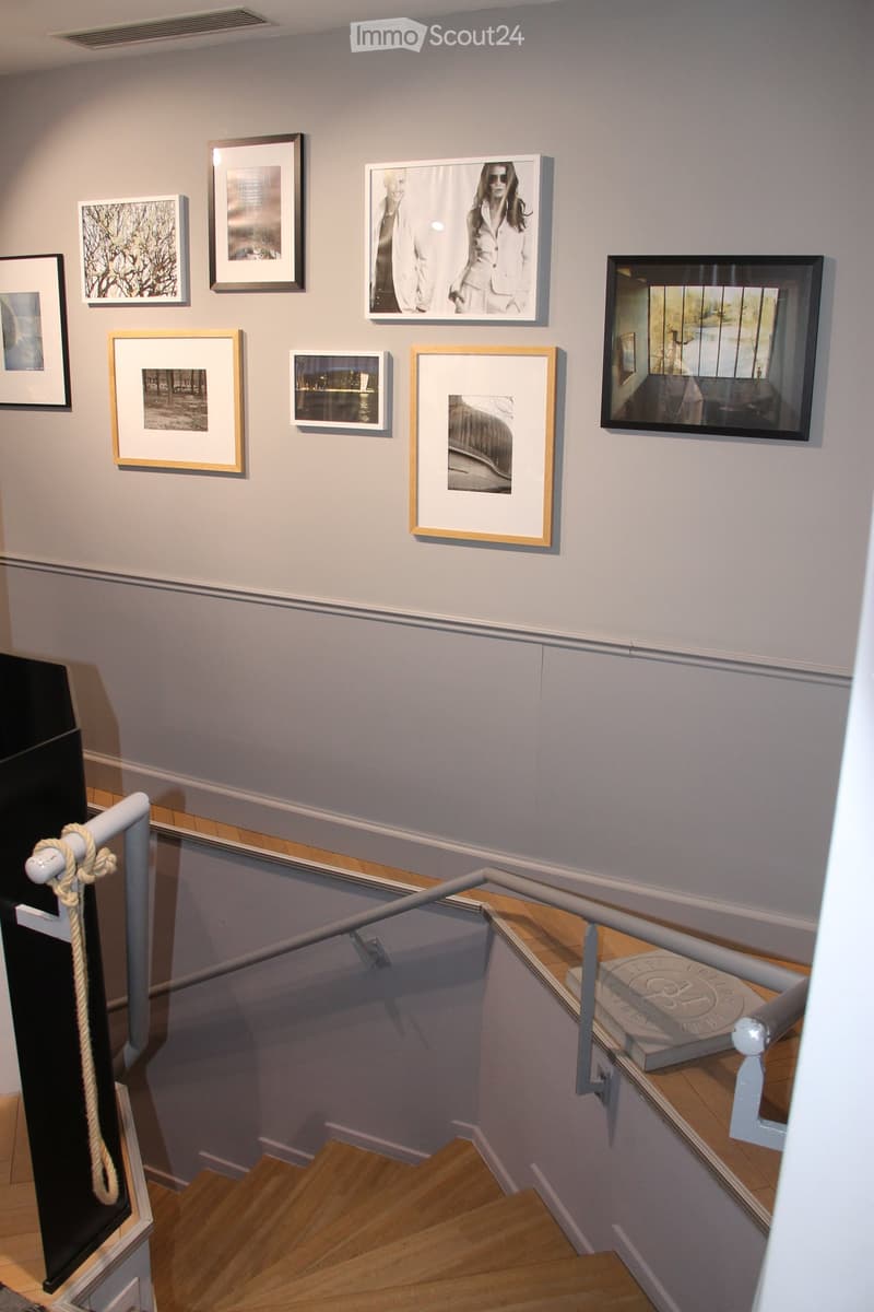 Staircase with wooden steps, metal railing, and framed artwork displayed on the wall.