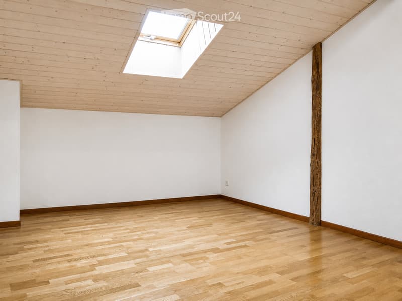 Empty room with wooden flooring, white walls, and a skylight window in the ceiling.