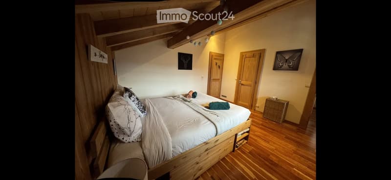Cozy bedroom with wooden bed, pillows, blanket, wicker basket, and two picture frames on the wall.