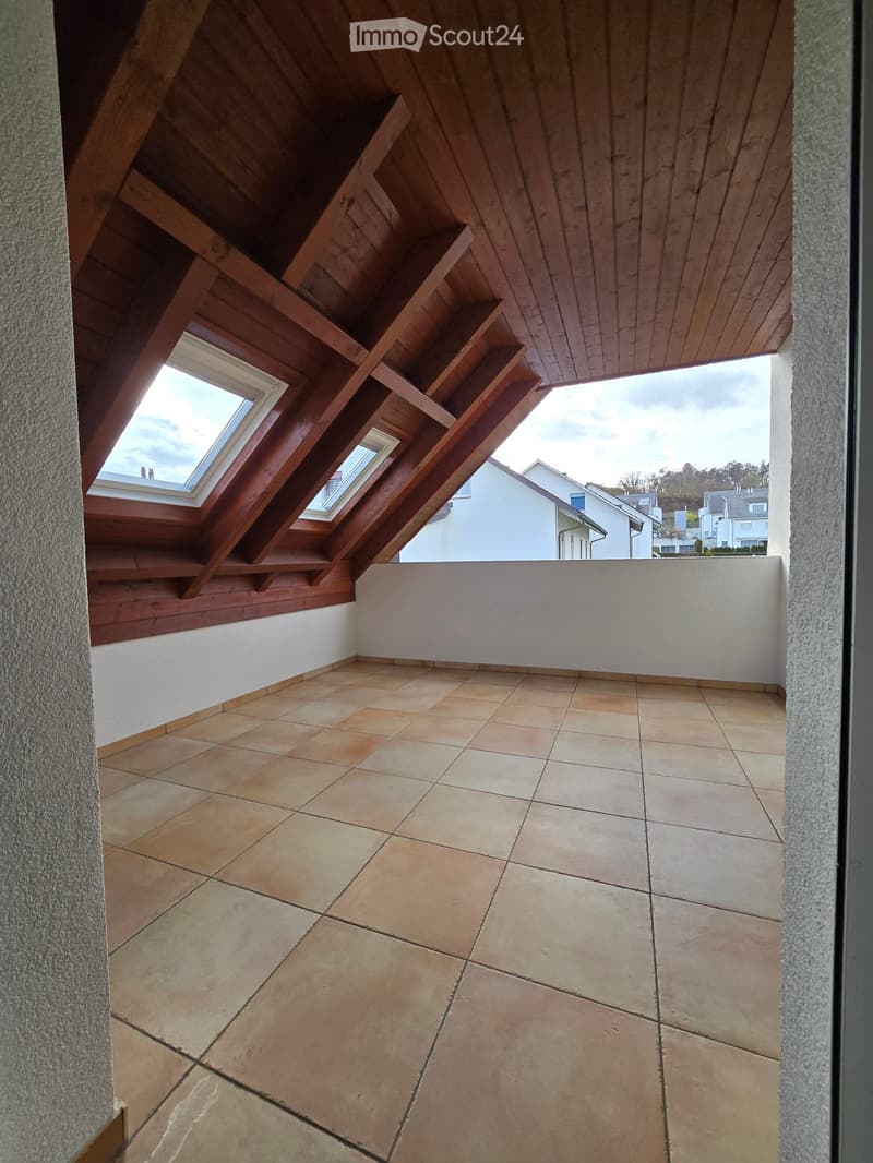 Balcony with wooden staircase leading up, tiled floor, white walls, and skylight windows offering a view of neighboring houses.