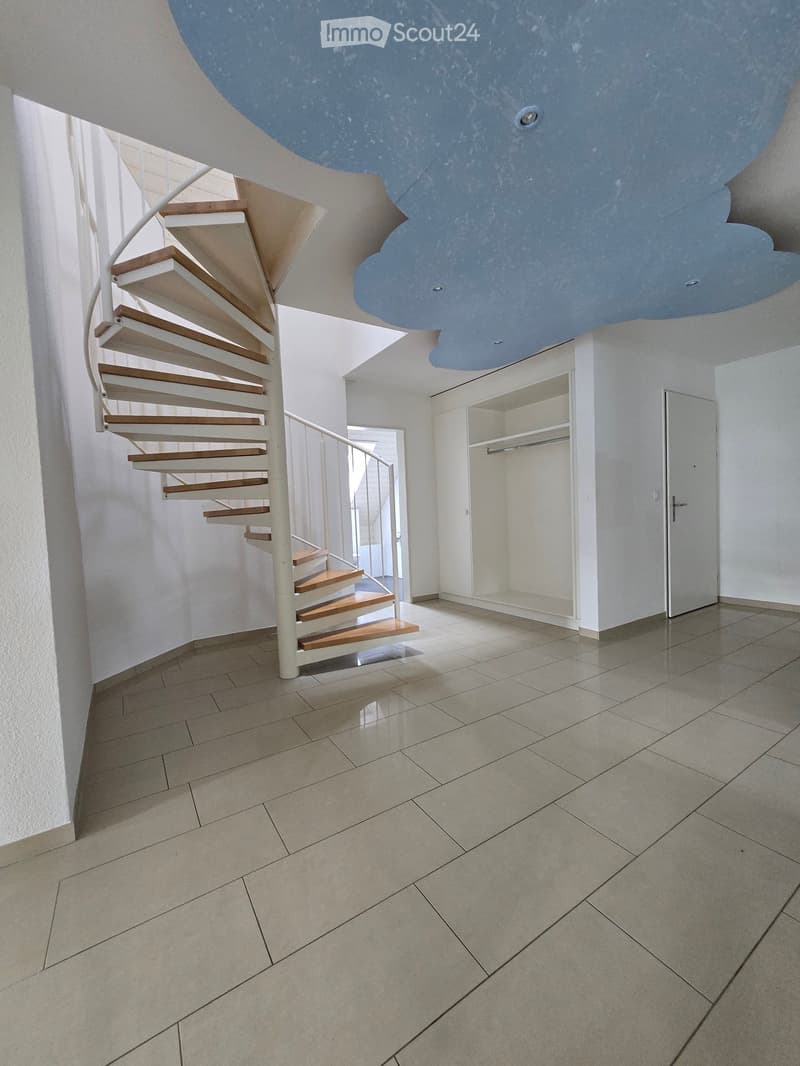 Modern hallway with a spiral staircase featuring wooden steps and a white railing, leading to an open area with white walls and tiled flooring.