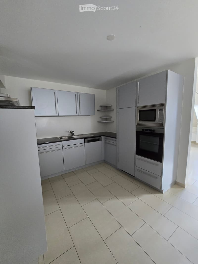 Modern kitchen with light grey cabinets, tiled floor, sink, microwave, oven, and dishwasher.