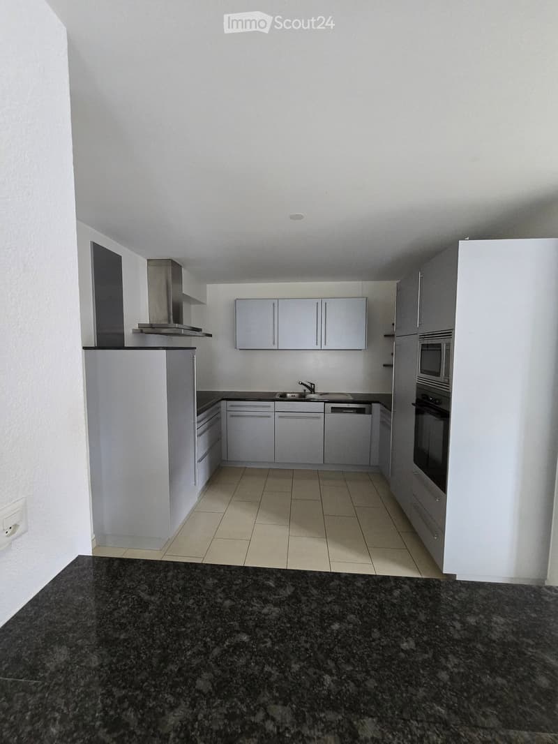 Modern kitchen with white cabinets, stainless steel appliances, granite countertop, and tiled floor.