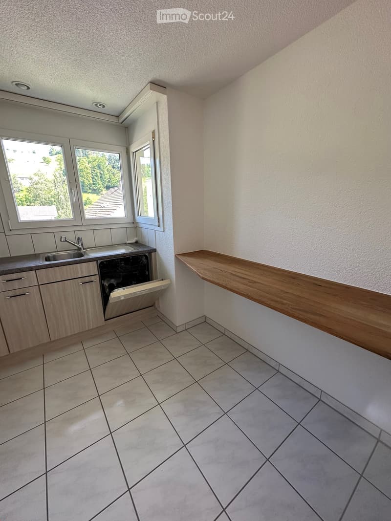 Modern kitchen with tiled floor, wooden cabinets, sink, faucet, dishwasher, and a wooden countertop.