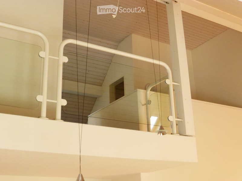 Modern interior with white railings, glass panels, and exposed wooden beams on the ceiling.