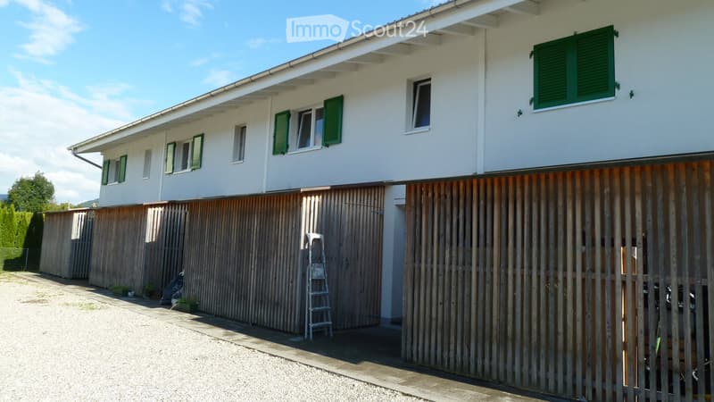 Two-story house with white exterior, green shutters, and a wooden fence in front.