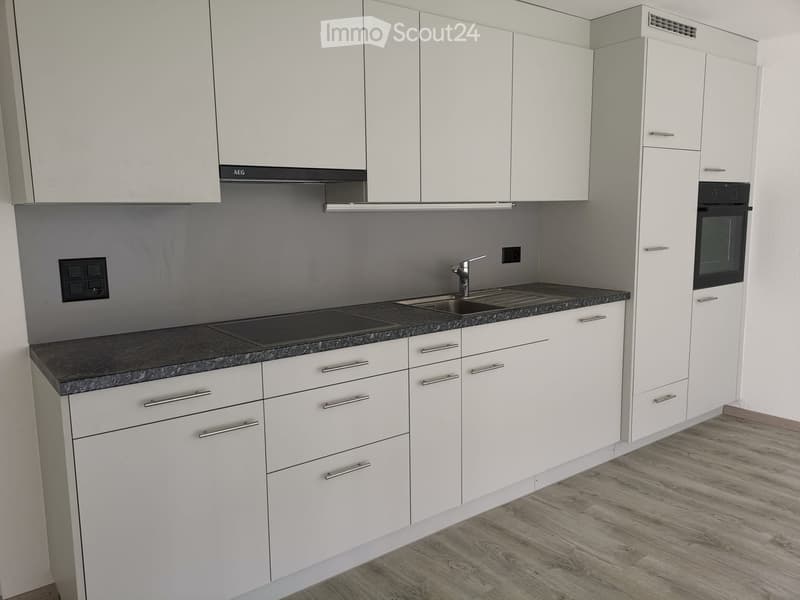 Modern kitchen with white cabinets, granite countertop, sink, faucet, and built-in oven.