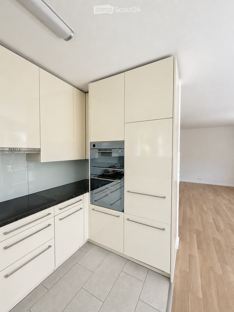 Modern kitchen with light-colored cabinets, stainless steel oven, and sleek countertops.