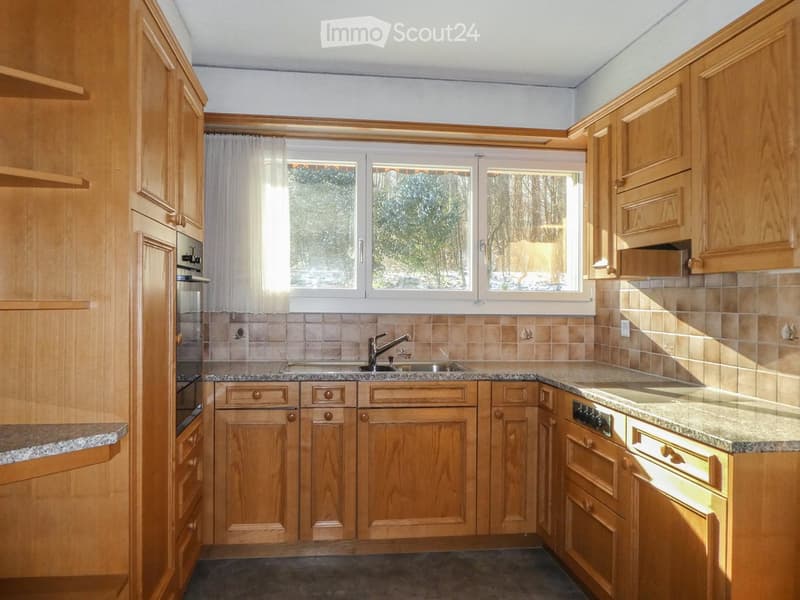 Bright kitchen with wooden cabinets, granite countertops, and a window view of the outdoors.