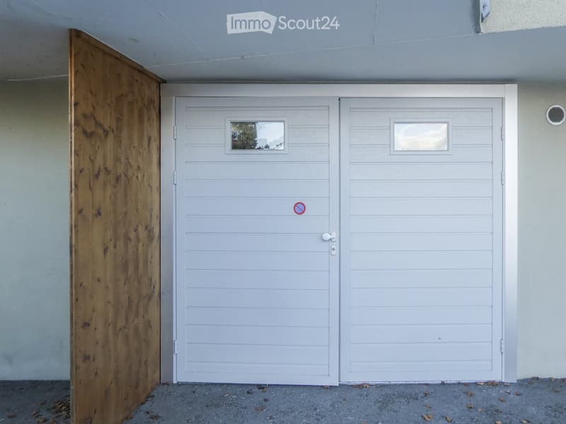 White garage door with two panels, small windows, and a no-parking sign.
