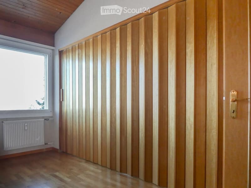 Empty hallway with wooden paneling, wooden floor, and a window on one side.