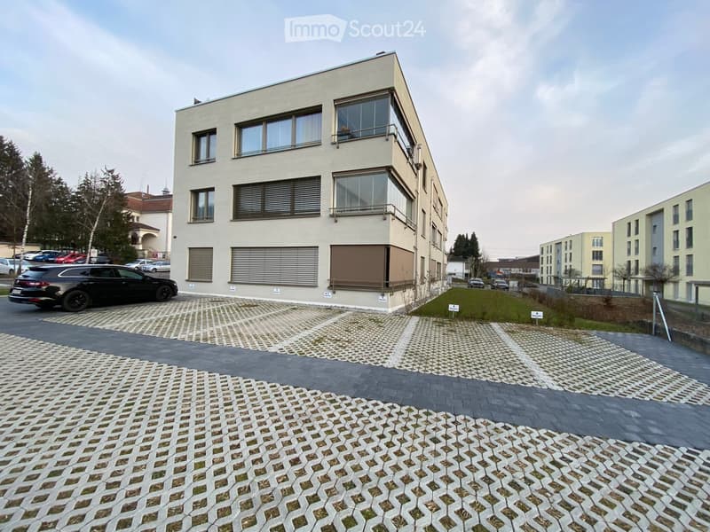 3 story building, white exterior, large windows, garage, parking lot