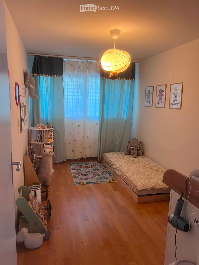 Cozy children's bedroom with a single bed, toy elephant, car track rug, bookshelf, and framed pictures on the wall.